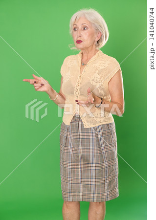 Mature woman in summer clothes looks and looks around on green background Mature woman in summer clothes looks and looks around on green background 141040744
