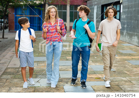 Group of positive cheerful teenagers hanging out on streets of city on day 141040754