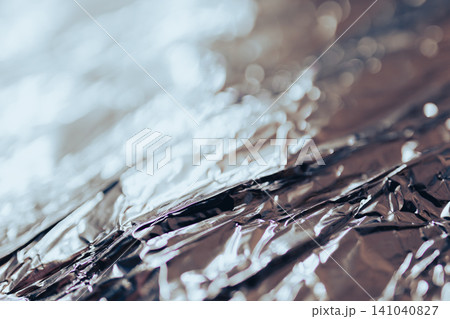 Abstract silver metal foil background with a crumpled surface and reflecting light, creating shiny textures and artistic bokeh effects for design Abstract silver metal foil background with a crumpled surface and reflecting light, creating shiny textures and artistic bokeh effects for design 141040827