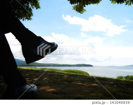 木陰で足を組んで海を眺める人の足元とエコパーク水俣の初夏の風景 141040839
