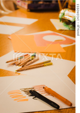 Artistic space with crayons and paper cutouts on a table, exploring creativity and learning through drawing in a home education environment. 141040933
