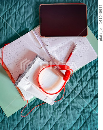 Student study setup for remote learning with tablet, textbooks, notebooks showing math equations, headphones and pen laid out on a bright bedspread for online classes and e learning Student study setup for remote learning with tablet, textbooks, notebooks showing math equations, headphones and pen laid out on a bright bedspread for online classes and e learning 141040952