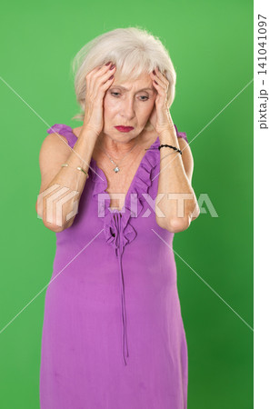 Upset and distressed senior woman person in pink dress, green screen 141041097