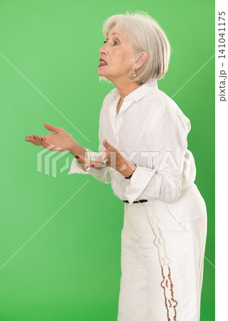 European senior woman in white suit on green screen background speaks or addresses imaginary partner European senior woman in white suit on green screen background speaks or addresses imaginary partner 141041175