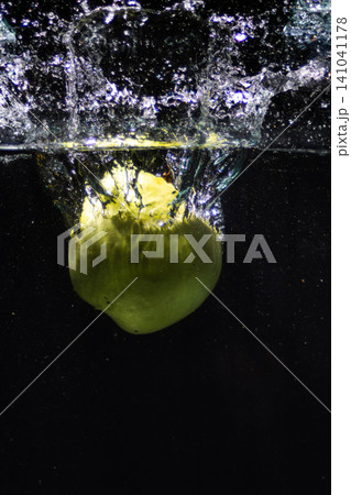 Green fruit splashing into clean fresh water creating bubbles Green fruit splashing into clean fresh water creating bubbles 141041178