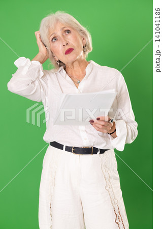 Upset and distressed senior woman person in white suit with document, green screen Upset and distressed senior woman person in white suit with document, green screen 141041186