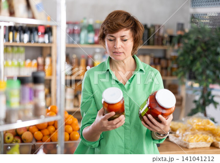 Woman make choice choose consider canned vegetables in store Woman make choice choose consider canned vegetables in store 141041212
