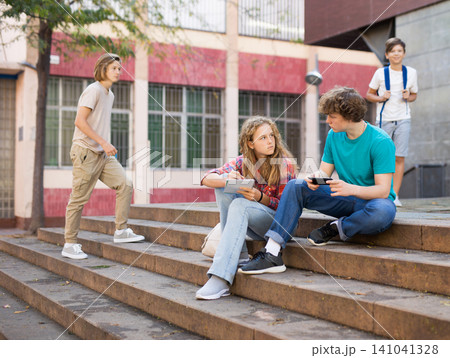 Boy and girl teens sitting on stairs and doing homework Boy and girl teens sitting on stairs and doing homework 141041328