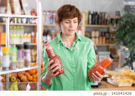 Adult woman chooses grapefruit and tomato juices 141041426
