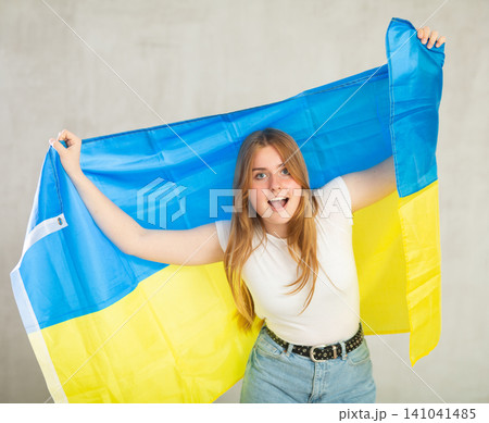 smiling girl in arms raised above head holds cloth of national flag of Ukraine smiling girl in arms raised above head holds cloth of national flag of Ukraine 141041485