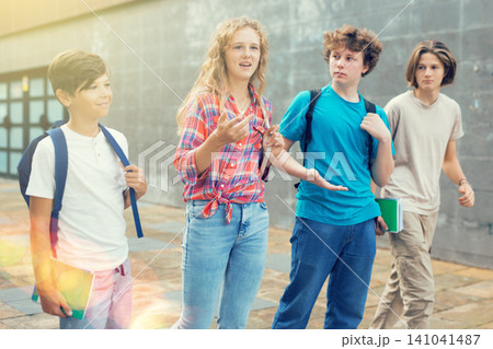 Four teenagers talking about play on walk in street 141041487