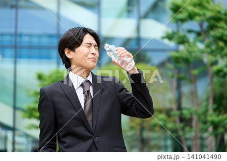 暑い屋外で水を飲むビジネスマン 暑い屋外で水を飲むビジネスマン 141041490