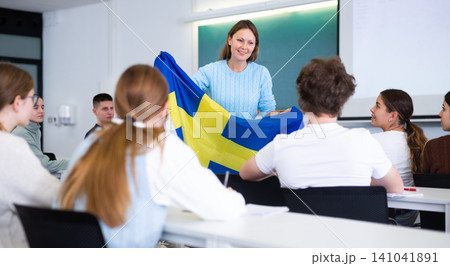 High school teacher tells students about Japan and holds a Japanese flag in hands. 141041891