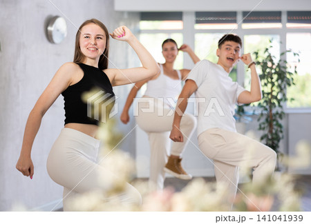 Cheerful teen girl enjoying while training movements of modern group dance in choreography class .. Cheerful teen girl enjoying while training movements of modern group dance in choreography class .. 141041939