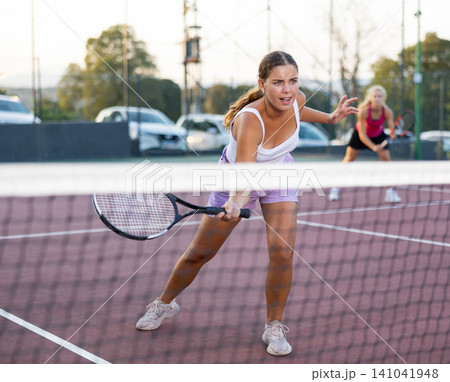 Positive female player hits ball close to net while playing tennis Positive female player hits ball close to net while playing tennis 141041948