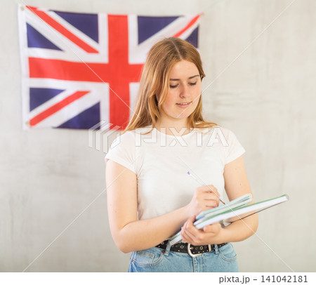 Satisfied female student with notebooks in her hands against the background of UK flag Satisfied female student with notebooks in her hands against the background of UK flag 141042181