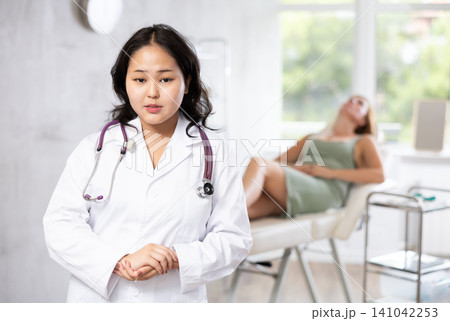 Asian professional cosmetologist advertising anti-aging skincare to patients Asian professional cosmetologist advertising anti-aging skincare to patients 141042253