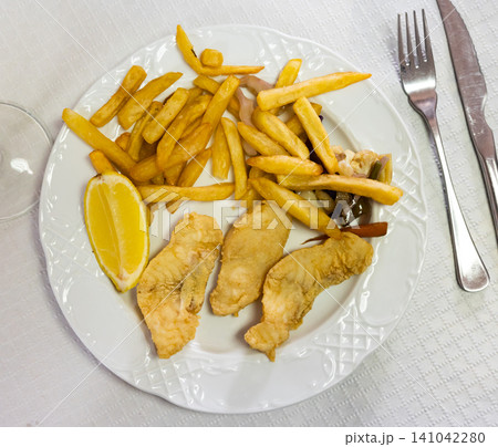 Battered fish with lemon and potatoes Battered fish with lemon and potatoes 141042280