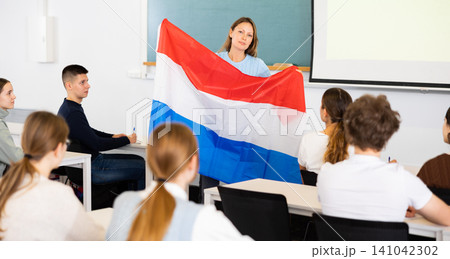 Geography lesson in school class - teacher talks about Netherlands, holding flag in his hands Geography lesson in school class - teacher talks about Netherlands, holding flag in his hands 141042302