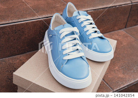 Elegant blue leather womens shoes blank product for branding displayed on recycled cardboard box. New casual female sneakers no-brand footwear e-commerce. No logo product unbranded fashion Elegant blue leather womens shoes blank product for branding displayed on recycled cardboard box. New casual female sneakers no-brand footwear e-commerce. No logo product unbranded fashion 141042854
