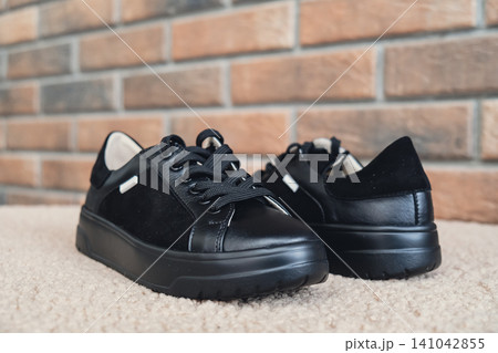 Elegant black leather womens shoes blank product for branding displayed. New casual female sneakers no-brand footwear e-commerce. No logo product 141042855