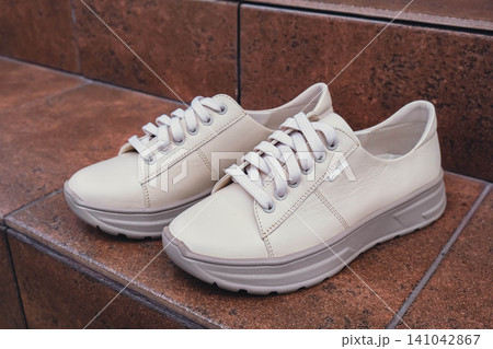 Fresh beige leather sneakers without brand marks displayed. For design templates online shops and sustainability-themed marketing. Clean blank sneakers Fresh beige leather sneakers without brand marks displayed. For design templates online shops and sustainability-themed marketing. Clean blank sneakers 141042867