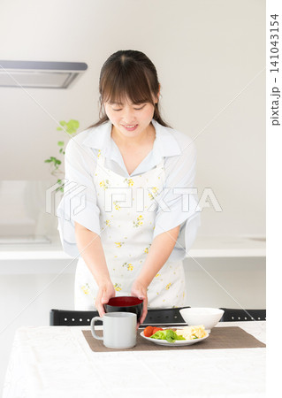 食卓に手料理を並べる母親・家族の夕食や家庭料理の準備をする女性 食卓に手料理を並べる母親・家族の夕食や家庭料理の準備をする女性 141043154