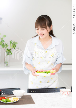食卓に手料理を並べる母親・家族の夕食や家庭料理の準備をする女性 食卓に手料理を並べる母親・家族の夕食や家庭料理の準備をする女性 141043156