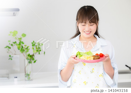 食卓に手料理を並べる母親・家族の夕食や家庭料理の準備をする女性 食卓に手料理を並べる母親・家族の夕食や家庭料理の準備をする女性 141043158