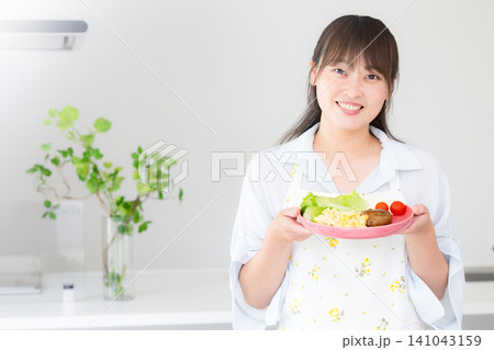 母親・家族の夕食や家庭料理の準備をする女性 主婦や家事代行などのイメージカメラ目線笑顔 母親・家族の夕食や家庭料理の準備をする女性 主婦や家事代行などのイメージカメラ目線笑顔 141043159