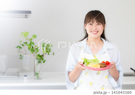 母親・家族の夕食や家庭料理の準備をする女性 主婦や家事代行などのイメージカメラ目線笑顔 母親・家族の夕食や家庭料理の準備をする女性 主婦や家事代行などのイメージカメラ目線笑顔 141043160