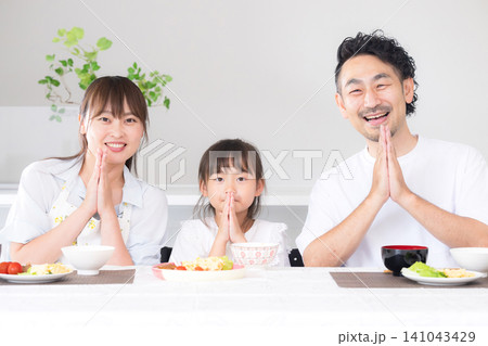 いただきますをしてダイニングで座る食事を始める親子3人の家族・食育や家族団らんのカメラ目線イメージ いただきますをしてダイニングで座る食事を始める親子3人の家族・食育や家族団らんのカメラ目線イメージ 141043429