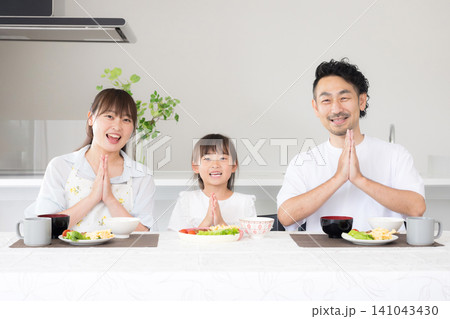 いただきますをしてダイニングで座る食事を始める親子3人の家族・食育や家族団らんのカメラ目線イメージ いただきますをしてダイニングで座る食事を始める親子3人の家族・食育や家族団らんのカメラ目線イメージ 141043430