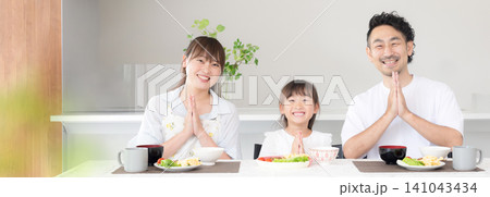 いただきますをしてダイニングで座る食事を始める親子3人の家族・食育や家族団らんのカメラ目線イメージ いただきますをしてダイニングで座る食事を始める親子3人の家族・食育や家族団らんのカメラ目線イメージ 141043434