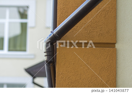 Roofing steel gutter rain system on building corner on light copy space background. Roofing, construction, drainage pipes installation concept. 141043877