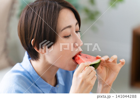 西瓜を食べる若い女性　ライフスタイルイメージ 141044288