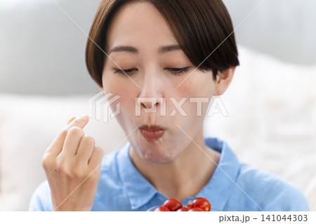 ミニトマトを食べる若い女性 ライフスタイルイメージ ミニトマトを食べる若い女性 ライフスタイルイメージ 141044303