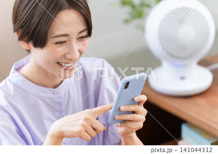 スマートフォンを操作する若い女性 ライフスタイルイメージ スマートフォンを操作する若い女性 ライフスタイルイメージ 141044312