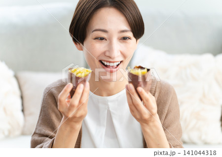 焼き芋を食べる若い女性　ライフスタイルイメージ 141044318