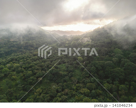 Evening clouds shroud green hills in a valley Evening clouds shroud green hills in a valley 141046234
