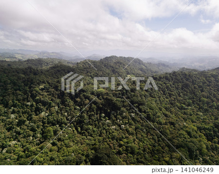 Lush green mountains stretch across the horizon under a cloudy sky 141046249