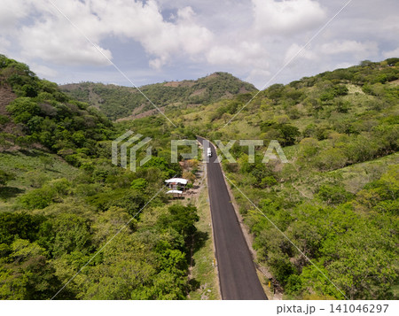 Truck travels on winding road through green hills in daytime Truck travels on winding road through green hills in daytime 141046297
