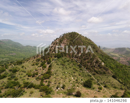 Hiking near a rocky hill with green landscape under a cloudy sky Hiking near a rocky hill with green landscape under a cloudy sky 141046298