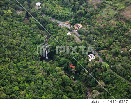 Forest with a waterfall and small houses near a winding road Forest with a waterfall and small houses near a winding road 141046327