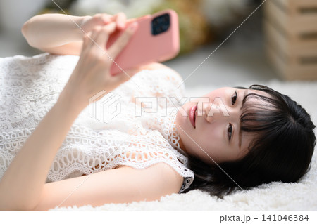スマホを見る横たわる女性 スマホを見る横たわる女性 141046384