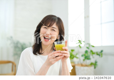 リビングで野菜ジュースを飲む60代の女性 リビングで野菜ジュースを飲む60代の女性 141047610