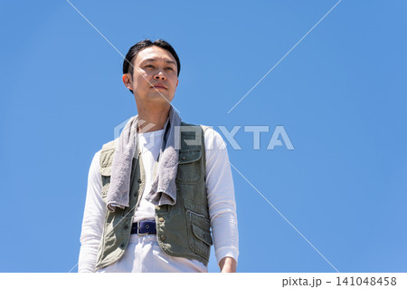 青空を背景に立つ作業着姿の男性作業員 青空を背景に立つ作業着姿の男性作業員 141048458