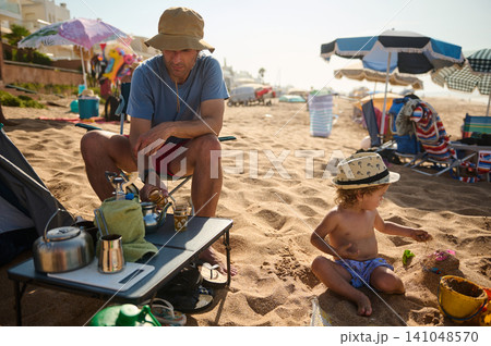 Father and toddler playing on sandy beach during relaxed summer family day by the sea Father and toddler playing on sandy beach during relaxed summer family day by the sea 141048570