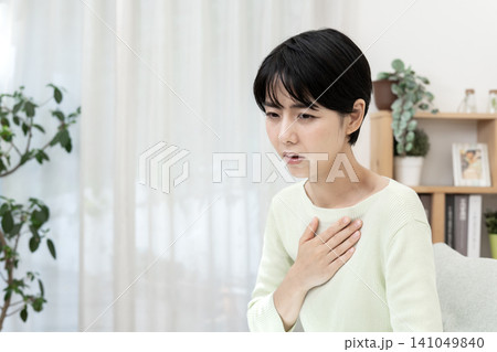 逆流性食道炎による胸焼けやムカムカ感に襲われ、胸元を押さえる若い女性 141049840
