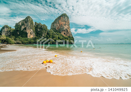 Scenic tropical beach with yellow buoys in the water and towering limestone cliffs in Scenic tropical beach with yellow buoys in the water and towering limestone cliffs in 141049925